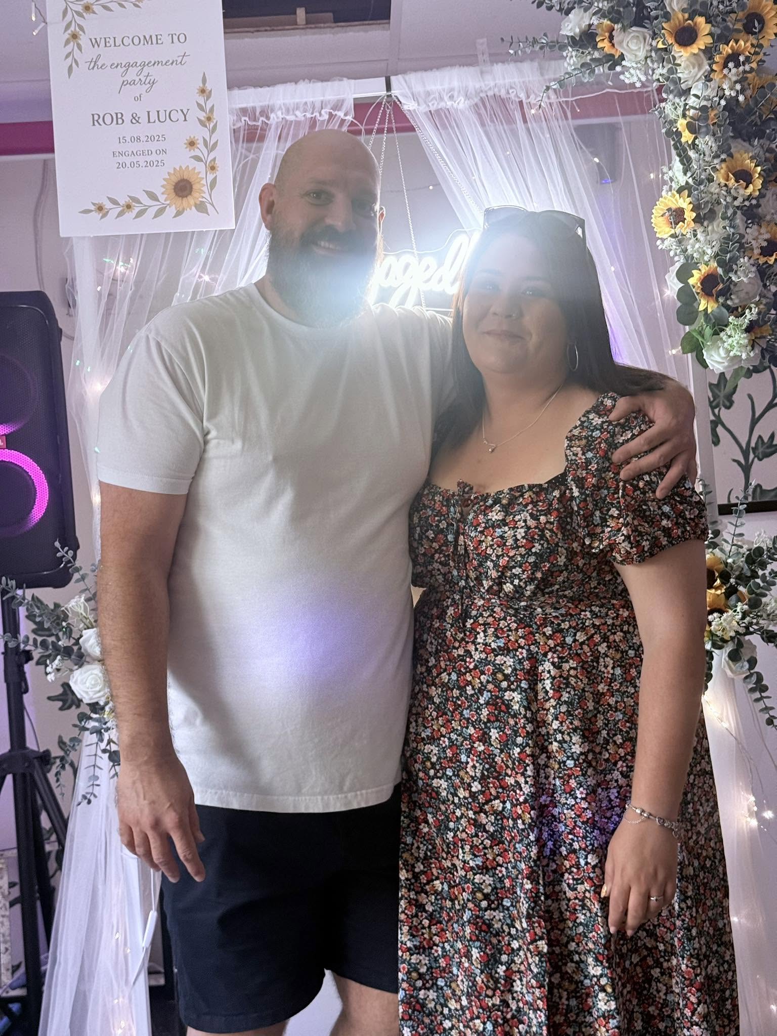 Rob and Lucy at their engagement party beneath the floral arch